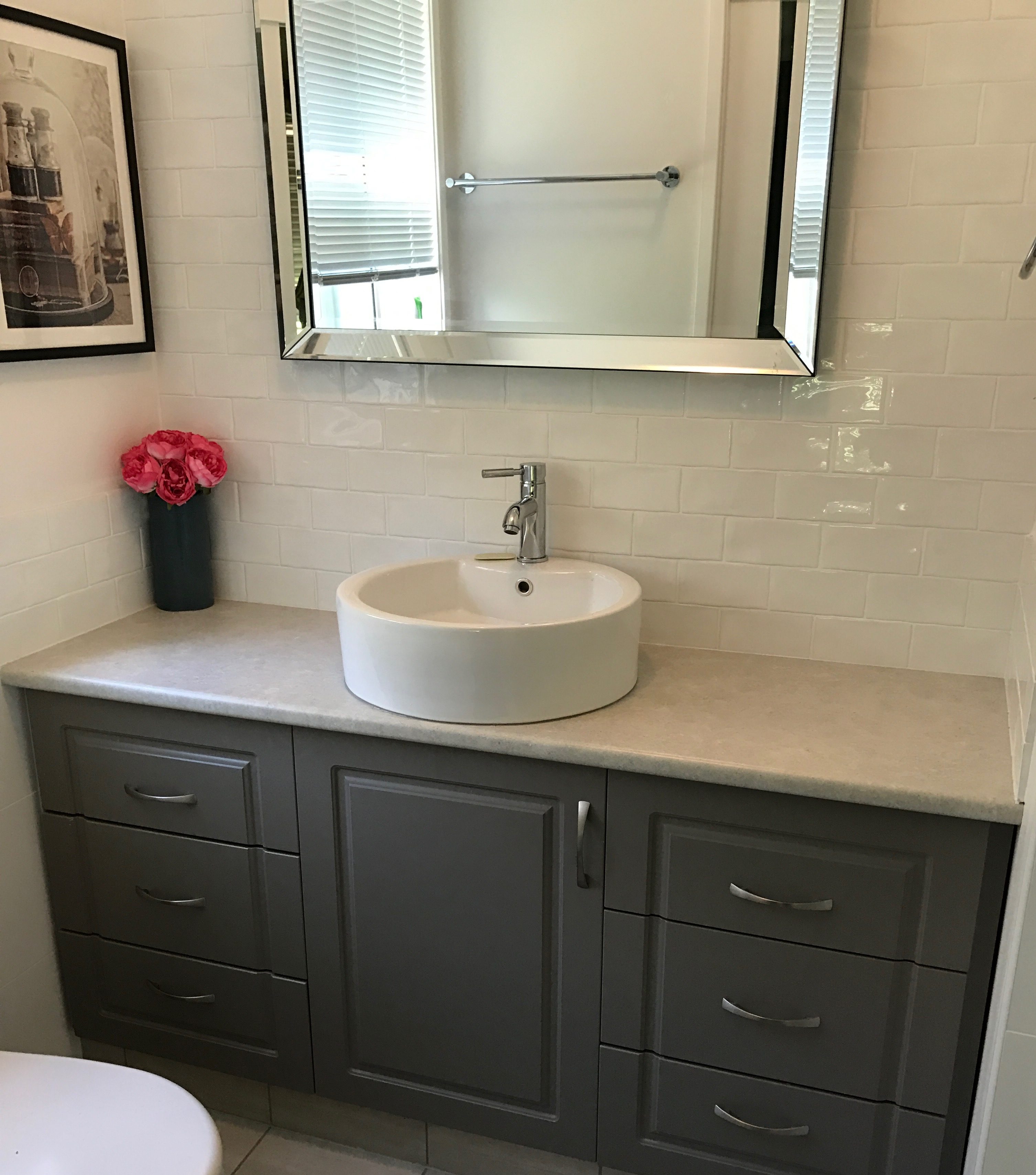 A round ceramic bathroom sink on  navy vanity unit